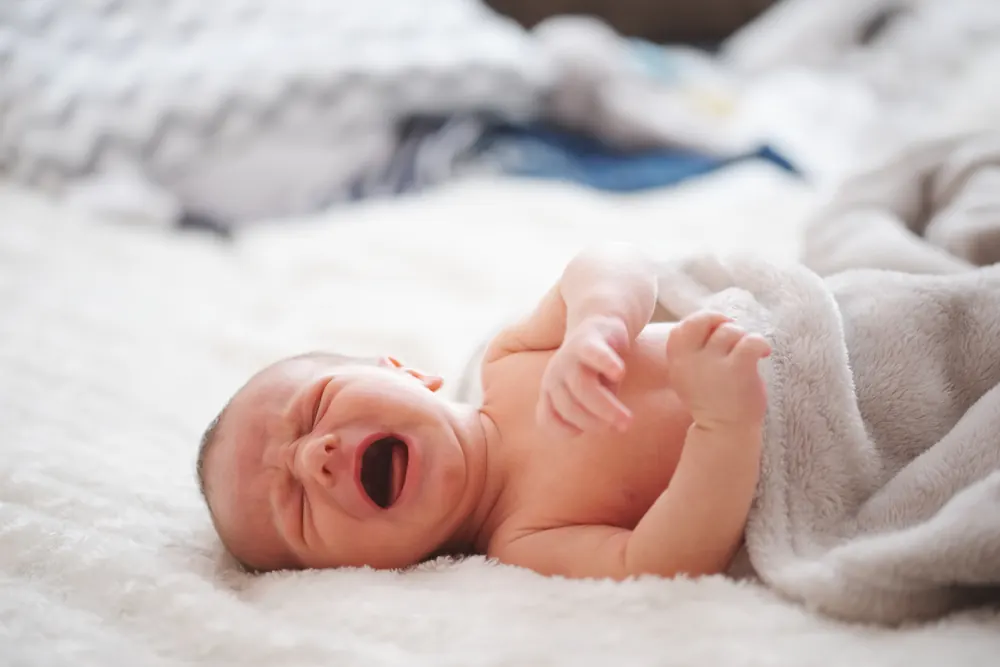 Baby liegt weinend im Bett: Beratung bei Schlafproblemen von Babys